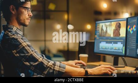 Late Evening Creative Office: Professional Videographer Works on Desktop Computer, Doing Footage Montage, Using Video Editing Software. Modern Video Stock Photo