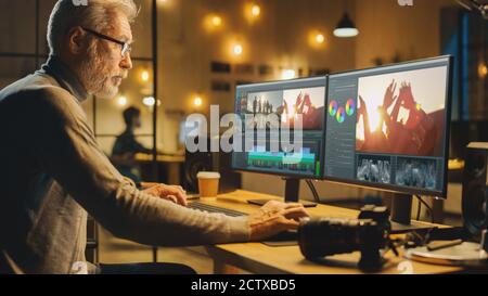 Evening in Creative Office: Professional Middle Aged Videographer Works on Desktop Computer, Doing Footage Montage, Using Video Editing Software Stock Photo