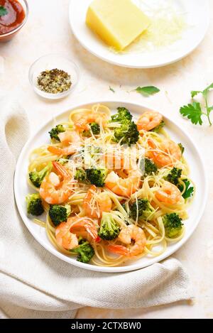 Shrimp and broccoli pasta on plate over light stone background. Tasty dish for dinner. Stock Photo