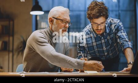 Chief Creative Designer Discusses Design Sheets with Young Developer. Two Professionals Having Discussion, Working with Documents, Choosing Right Stock Photo