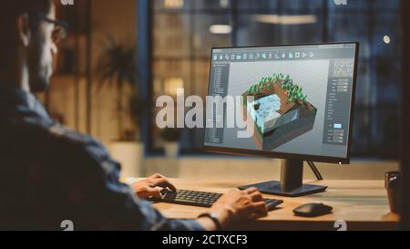 In the Evening Creative Young Video Game Developer Works on a Desktop Computer with Screen 3D Videogame Level Design. Stylish Creative Studio Office Stock Photo