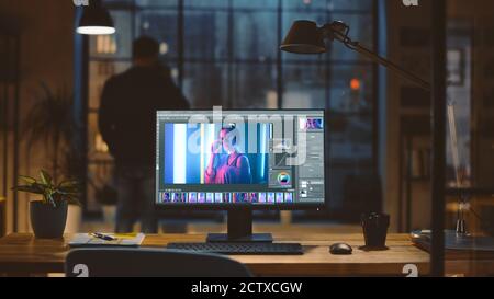 Desktop Computer with Photo Editing Software Standing on the Desk in the Modern Creative Office. In the Background Designer Drinks from a Cup Looks at Stock Photo