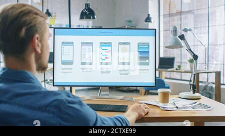 Young Professional Works on a Personal Computer at His Desk in the Creative Office. Notebook Screen Shows Mobile Phone Application Design, Software UI Stock Photo