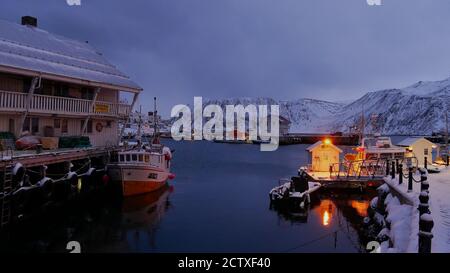 Blue hour photo before dark of illumineted harbor with fishing vessels in Honningsvag, Norway in winter time. Stock Photo