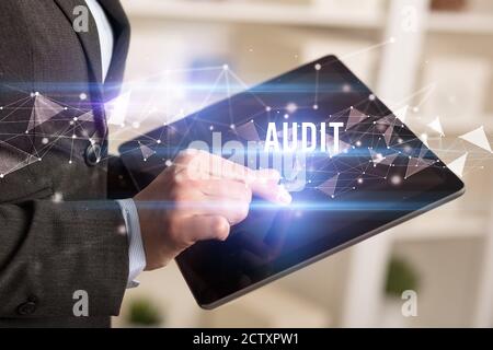 Close up hands using tablet with AUDIT inscription, modern business technology concept