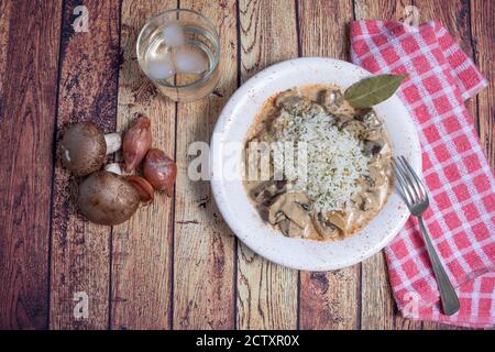 Mushroom beef stroganoff, with cremini and champignons, in a frying pan, shot from above, cenital view, on a dark rustic texture with a place for text