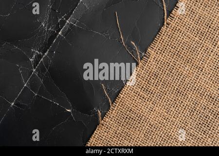 Burlap on black crumpled paper with wrinkles and folds. Abstract background with sackcloth on grunge backdrop Stock Photo