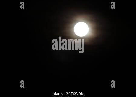 The full moon shining through cloud cover Stock Photo