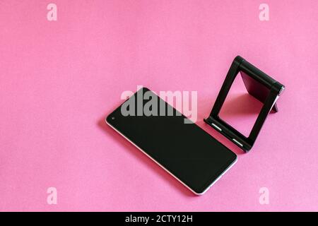 Flat lay photo with smartphone, phone stand on the pink background. Modern technologies concept. Stock Photo