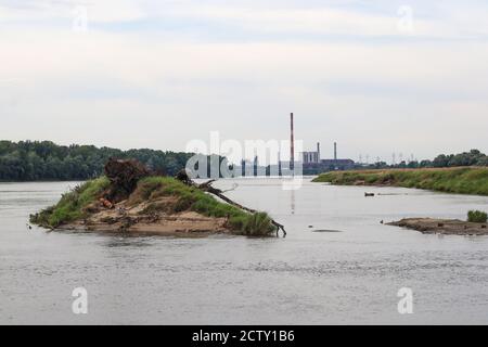 View along wide river with small island on foreground and huge heat and power plant on background Stock Photo