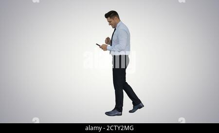Man walking looking on phone and making win gesture on gradient Stock Photo