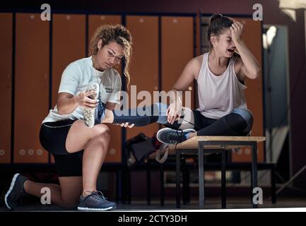 Young injured girl getting help from her personal trainer after a strenuous training Stock Photo