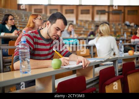 Male student focused on the lesson at the lecture in the university classroom Stock Photo