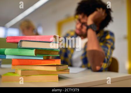 A lot of books in front of male student at the university classroom Stock Photo