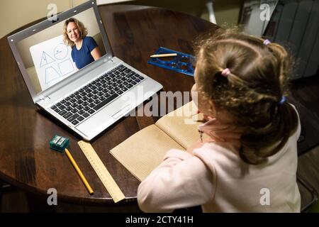 Kid virtual learning with teacher by laptop, tutor teaches preschool child during quarantine due to coronavirus. Concept of distance lesson, online ho Stock Photo