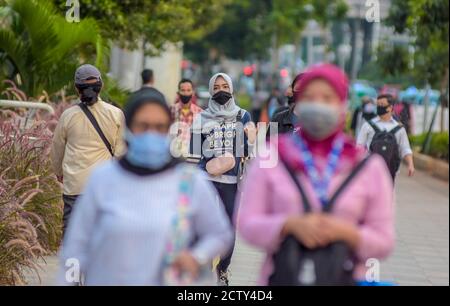 Office workers walking at sudirman street with face mask to prevent the transmission of coronavirus Stock Photo