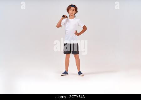 Little tennis player. Full-length shot of a confident teenage boy holding tennis racket and looking at camera isolated over grey background Stock Photo