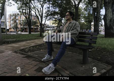 Young Hispanic man sitting on a bench and having a rest Stock Photo