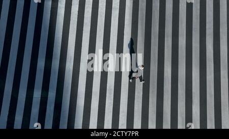 Elevated view over a man on pedestrian crossing in road intersection of Japan. Aerial view of people at crosswalk. Asia downtown. Metropolitan Tokyo C Stock Photo