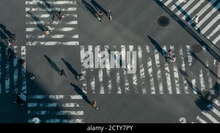 Elevated view over a crowd of japanese pedestrian crossing in road intersection with light of a sunset. Aerial view of asian people in busy scramble c Stock Photo