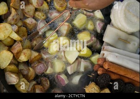 Fried potatoes and snacks on the grill in a street market, Old Town, Lijiang, Yunnan Province, China Stock Photo