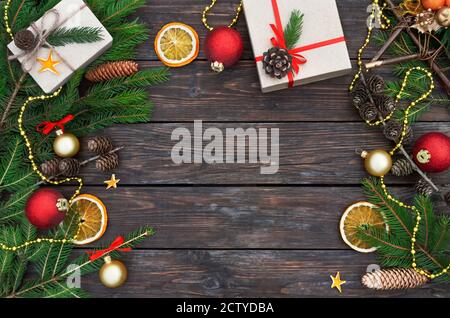Christmas or New Year composition. Gift boxes with fir branches, cones and decorations on vintage wooden background with copy space. Top view. Stock Photo