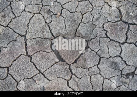 Dry cracked earth with a heart shaped center. Stock Photo