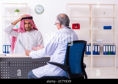 The young male arab visiting experienced male doctor Stock Photo