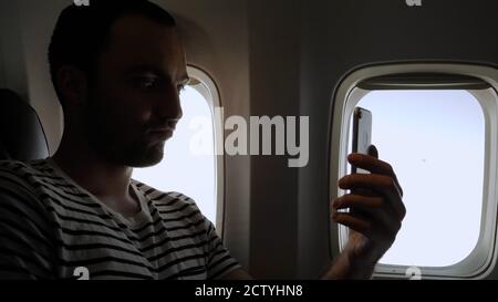 Man take funny selfie travelling in the airplane. Stock Photo