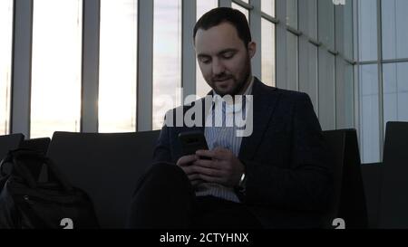 Business man messaging through his mobile phone while sitting in Stock Photo