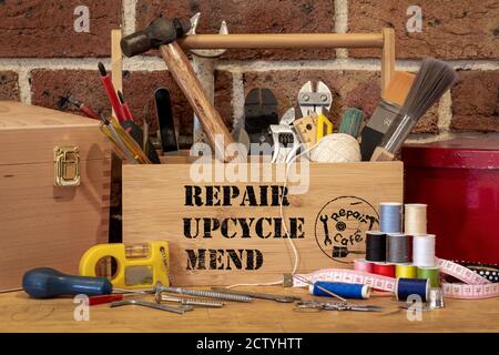 tool box with repair, upcycle, mend stencil text surrounded by repair tools on bench, consumer activism to repair household items to reduce waste and Stock Photo