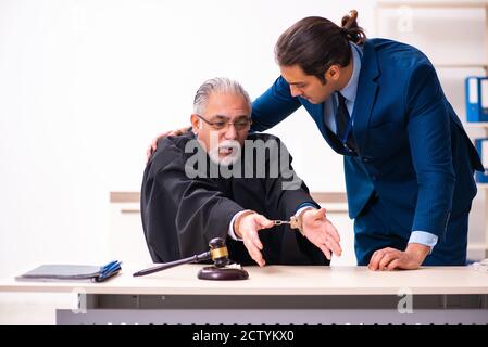 Police inspector arresting judge in court Stock Photo