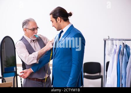 Young businessman visiting old tailor Stock Photo