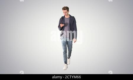 Young man in casual clothes text messaging on cell phone and wal Stock Photo
