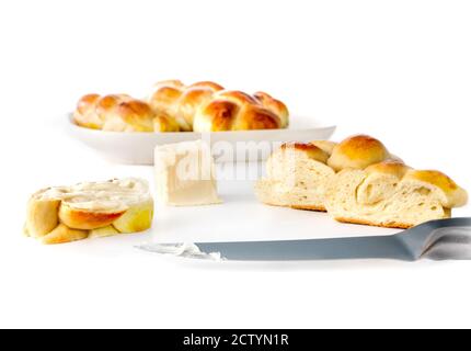 Multiple small braided buns, whole and sliced, with butter and knife. Concept for traditional breakfast table. Authentic Swiss butter bread recipe. Stock Photo