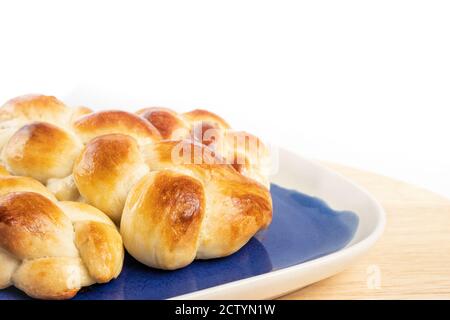 Multiple small braided buns. White yeast bread with egg wash on blue and white plate. Perspective view. Authentic Swiss butter bread recipe called Zop Stock Photo