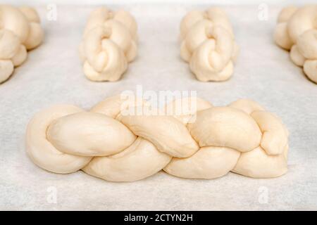 Homemade yeast dough braided in single portion buns. Traditional Swiss butter bread recipe called Zopf or Butterzopf. Braided small bread loafs. Stock Photo