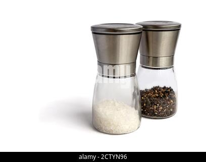 Salt and pepper mill set. Isolated on white. Glass and stainless steel grinders. Filled with coarse white salt grind and whole black peppercorn. Stock Photo