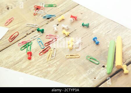 Set of colorful pencils and brown lying in row on table with white paper sheet with pins Stock Photo