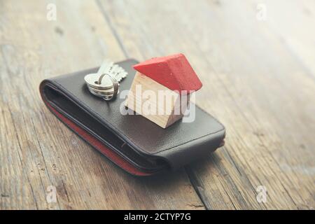 house and key on wallet on wooden table Stock Photo