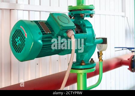 Green electric motor with pump on hot water pipeline. Stock Photo