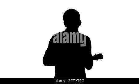 Silhouette Young man playing ukulele and signing while walking a Stock Photo