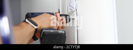 Master holds screwdriver in his hands and drills hole Stock Photo