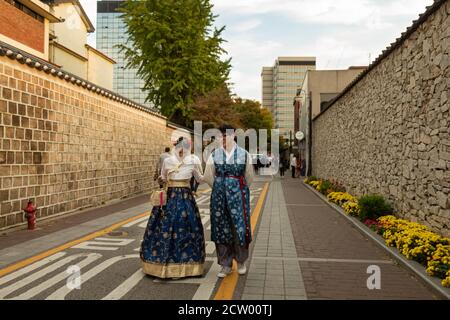 Seoul, South Korea - October 19th 2017: A Korean couple in traditional hanbok dress walking along an alley at sunset, Seoul, South Korea Stock Photo