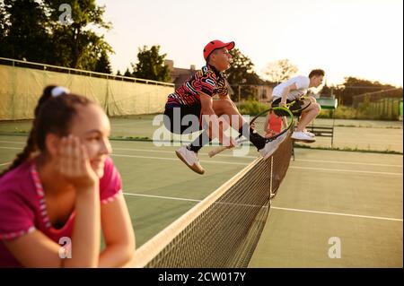 Mixed doubles tennis, players jump through the net Stock Photo