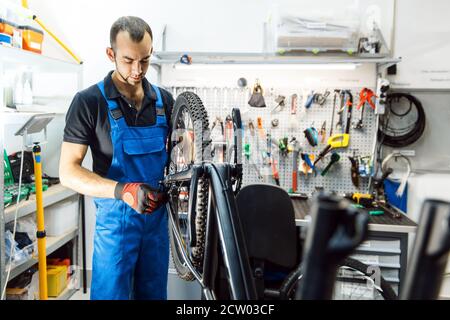 Bicycle assembly in workshop, man installs wheel Stock Photo