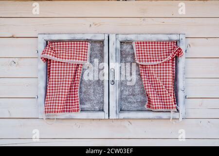 Wooden window on the wall of wooden boards with checkered napkins in red. Stock Photo