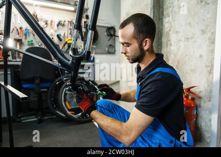 Bicycle repair in workshop, man fixing crank Stock Photo