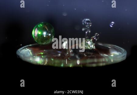 Colored crystal ball colliding in the water and water bubbles bouncing in the air Stock Photo