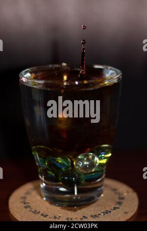 splash of drops in a glass of water and marbles or colors glass balls Stock Photo